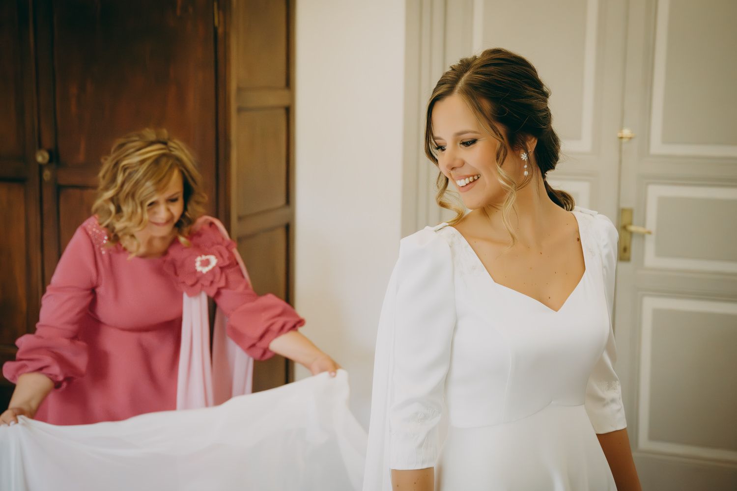 Preparativos finales del vestido con un impresionante vestido blanco y detalles en rosa.