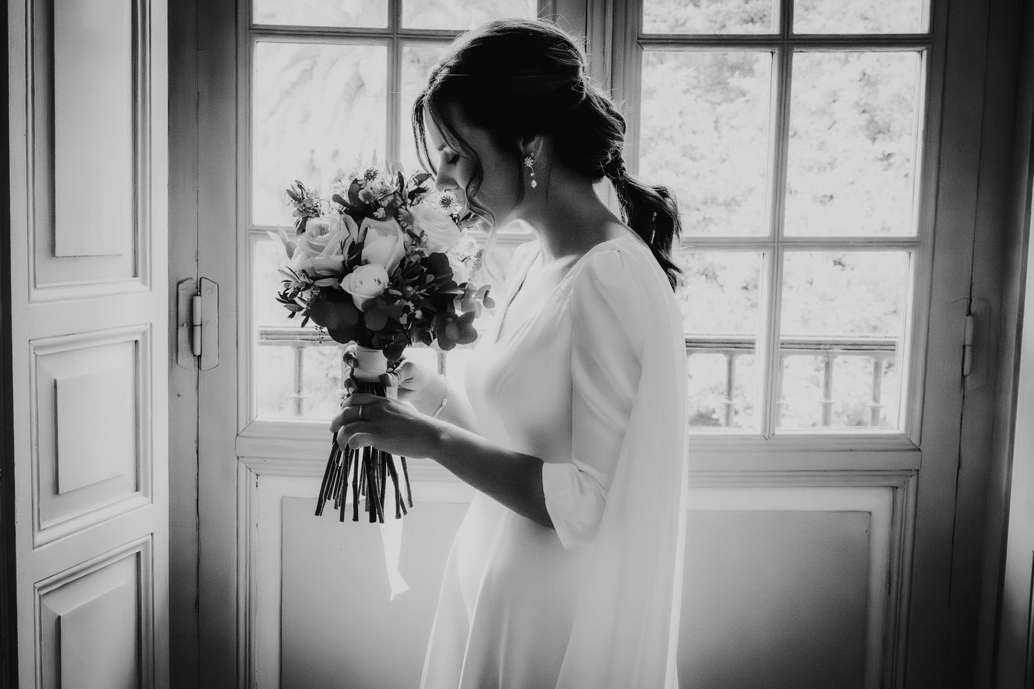 Retrato en blanco y negro con delicado ramo junto a una ventana vintage del Palacio de Villabona