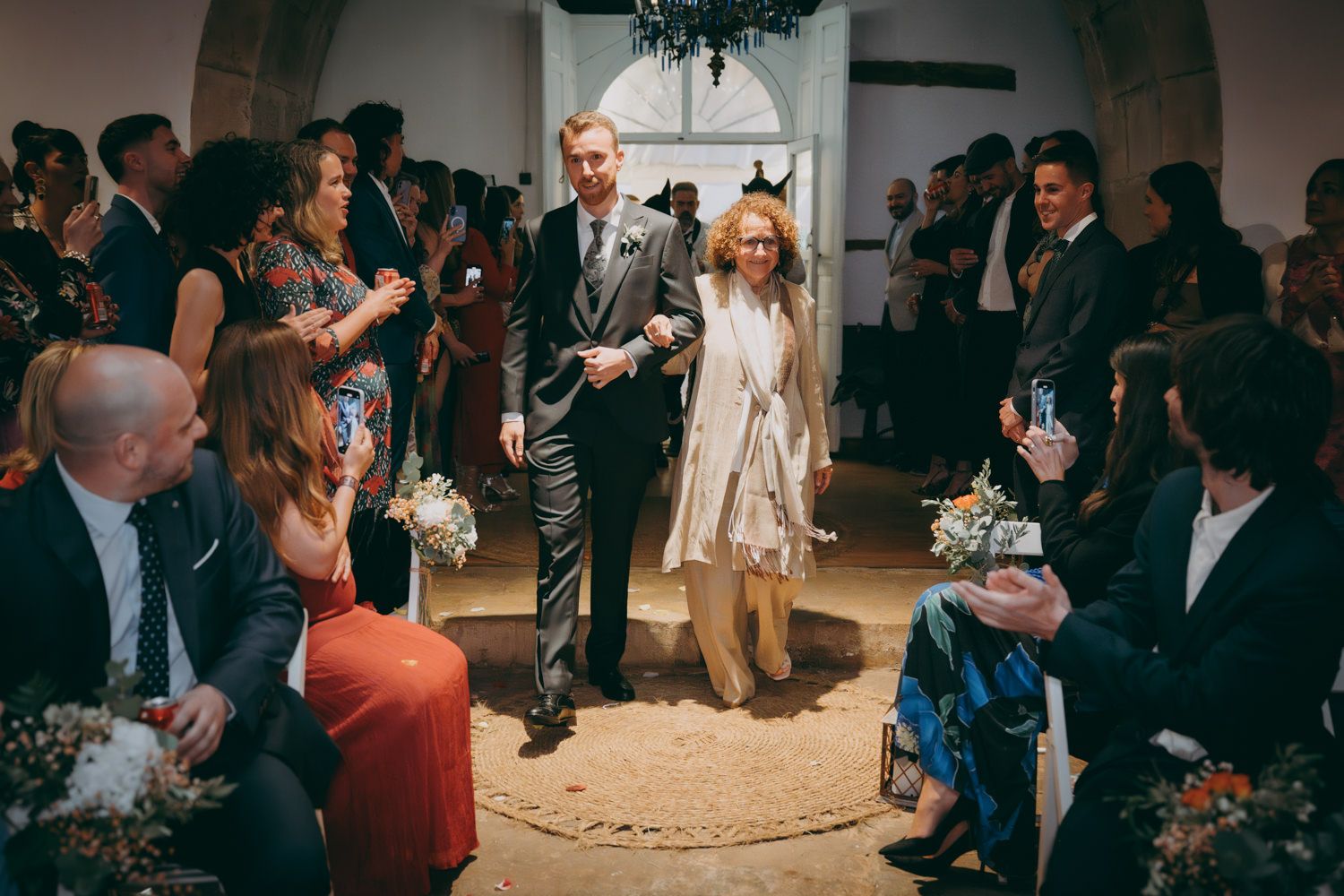 Ceremonia de boda íntima en interiores con arquitectura rústica arqueada e invitados reunidos.