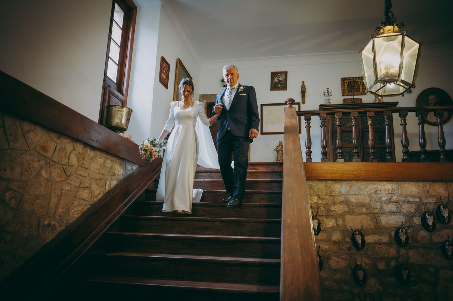 Padre y novia descendiendo una elegante escalera de piedra en el palacio de Villabona.