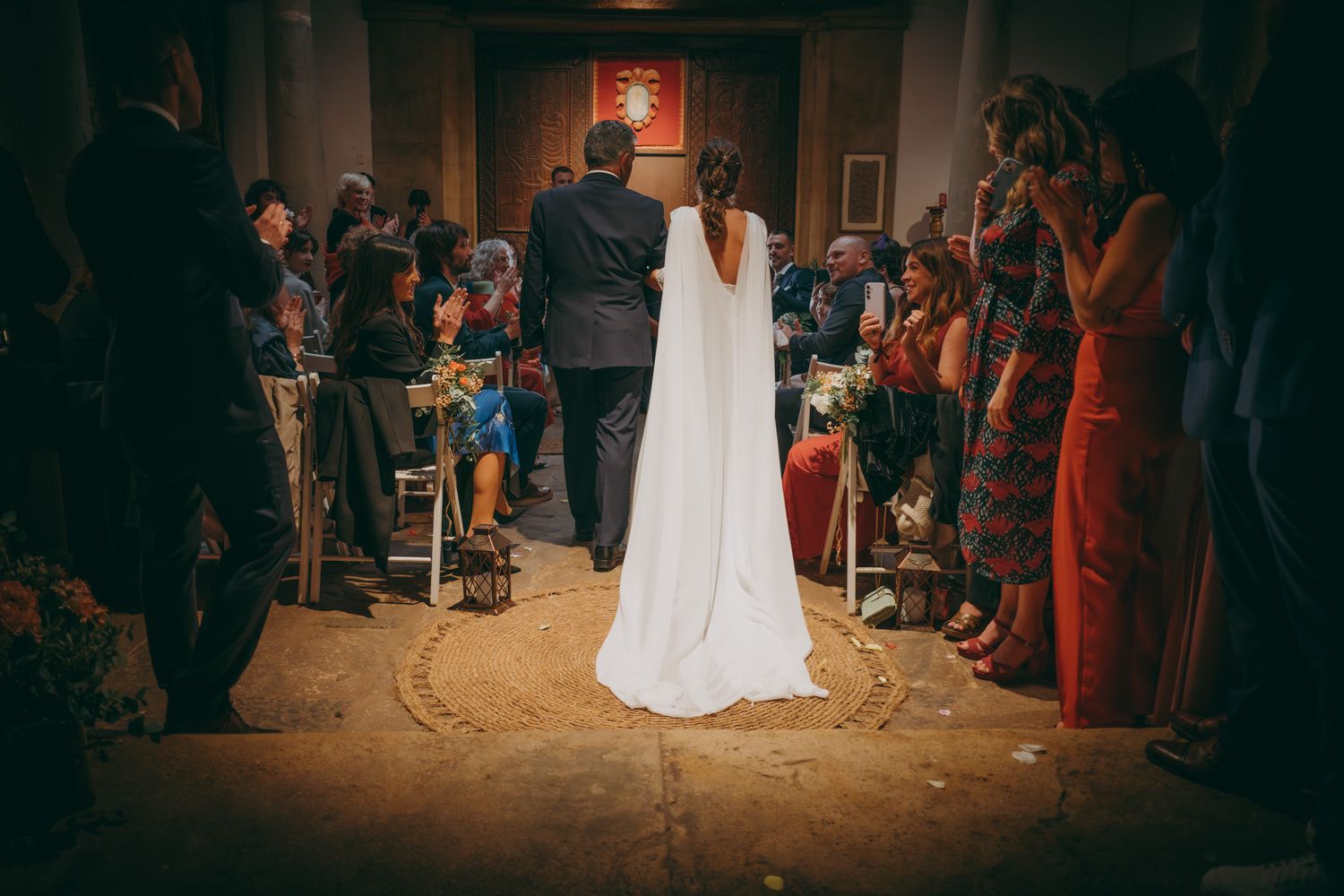 Vista desde atrás de la ceremonia de la boda con invitados sentados en un lugar interior íntimo.