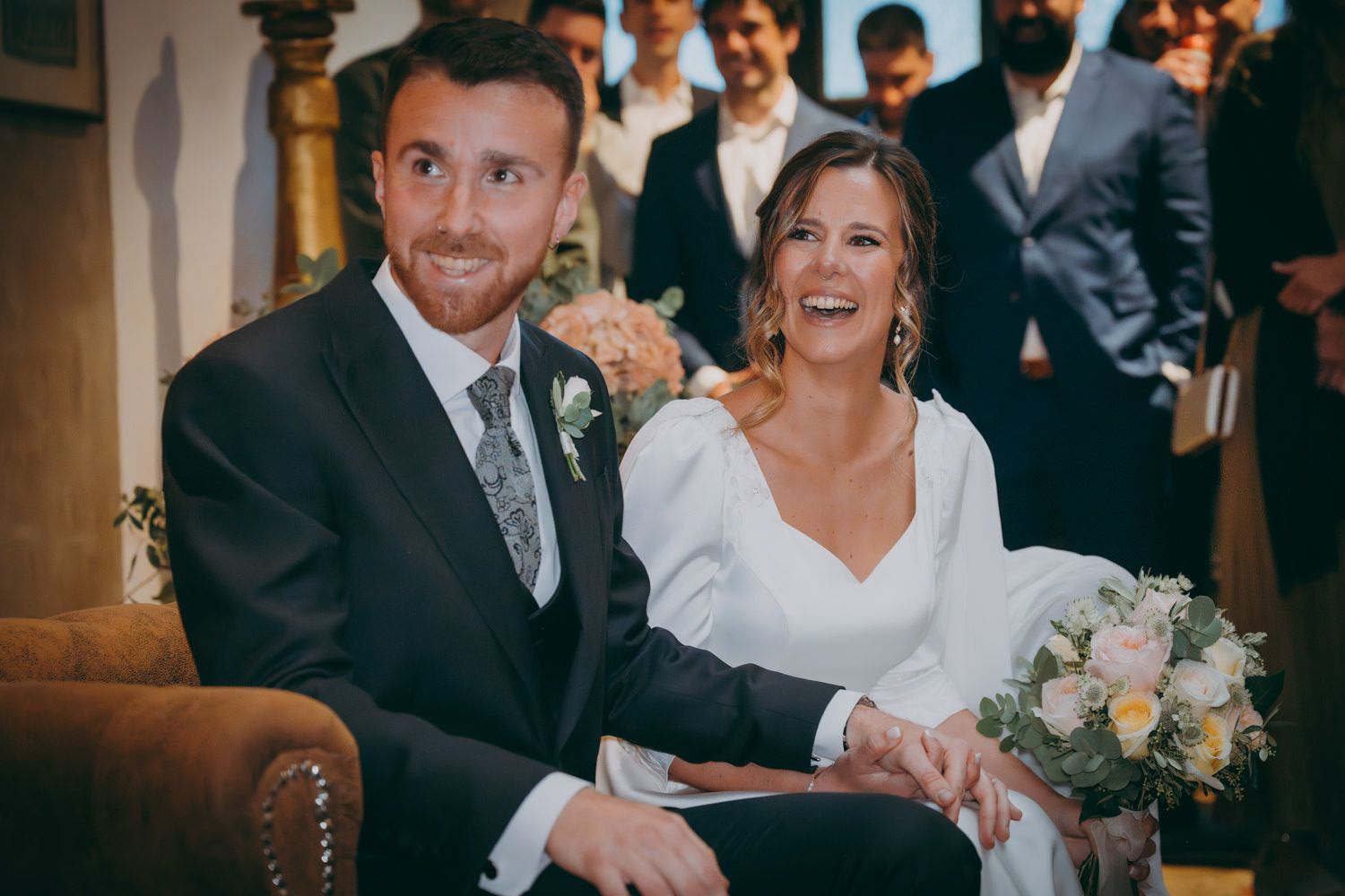 Feliz pareja compartiendo risas durante la ceremonia de boda en un lugar tradicional.