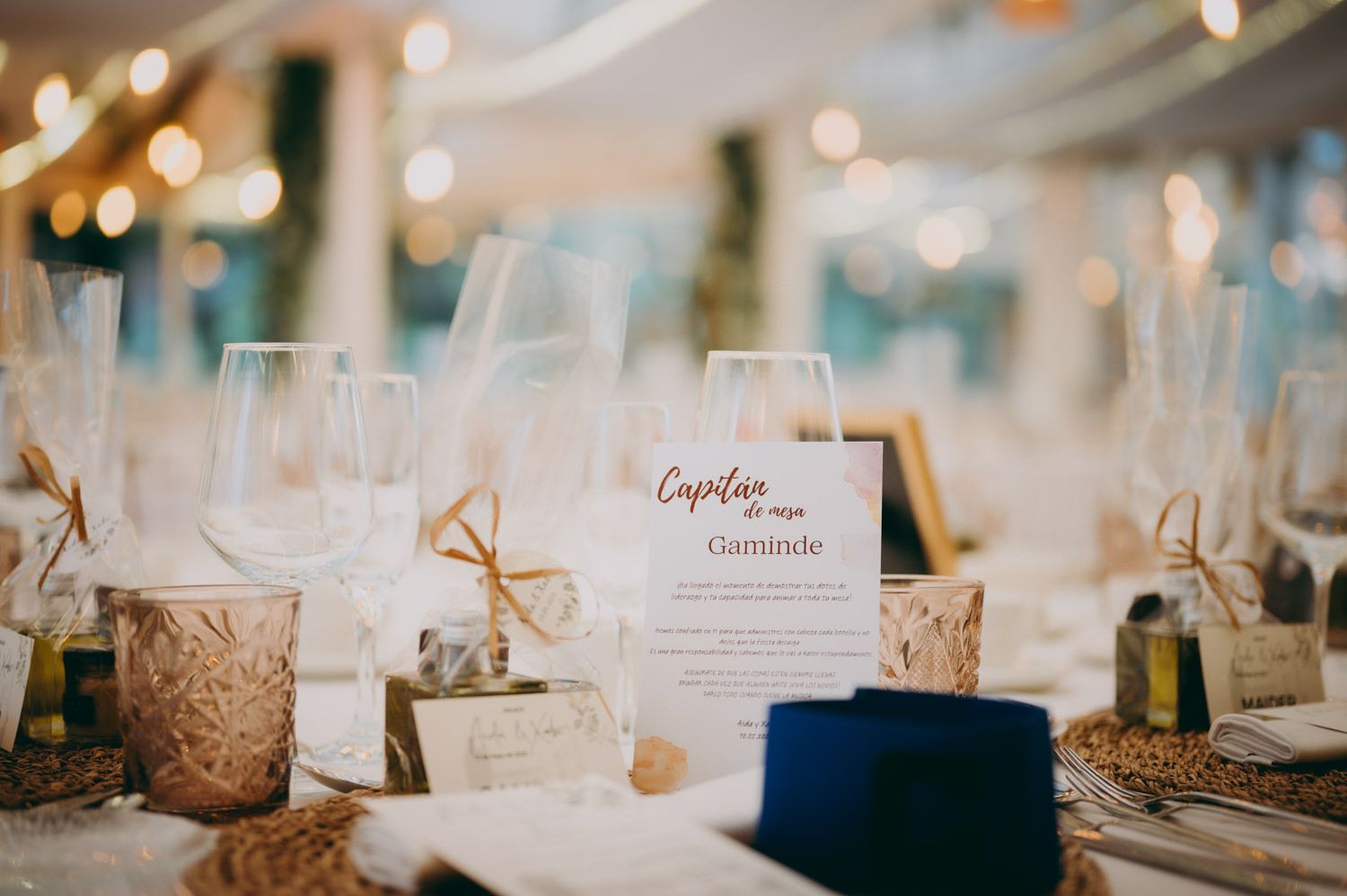 Elegante mesa de boda con tarjetas de nombre, copas de vino y detalles dorados.