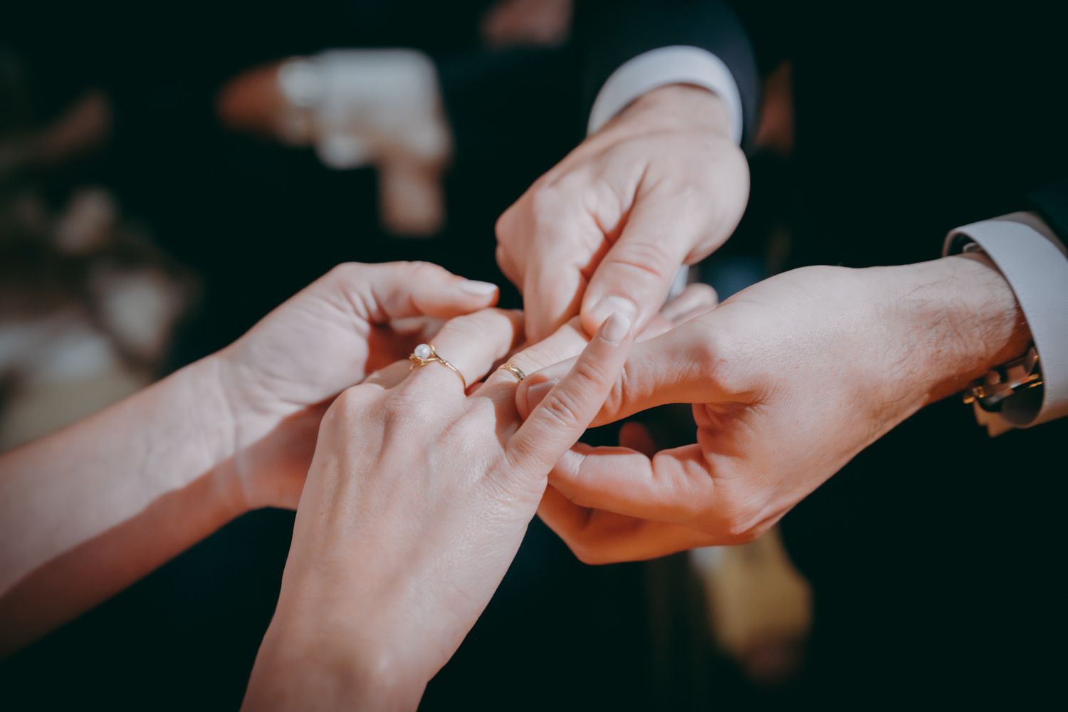 Primer plano de manos intercambiando anillos durante el momento íntimo de la ceremonia de boda.