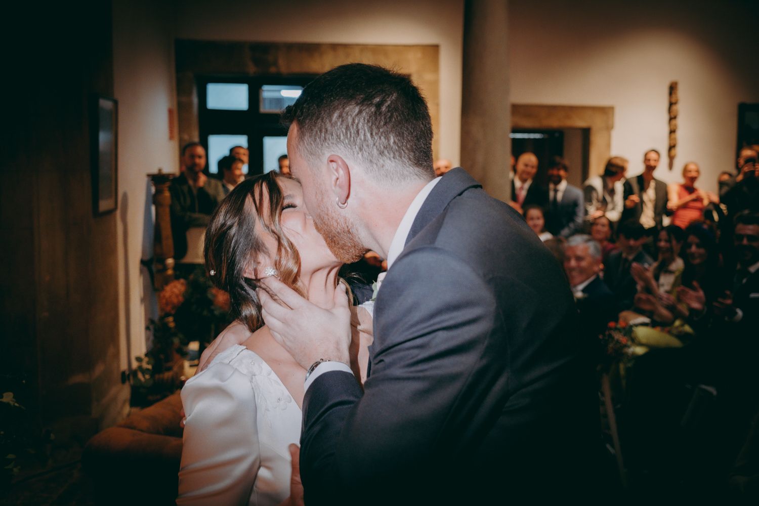 Momento romántico del primer beso entre los recién casados frente a los invitados a la boda.
