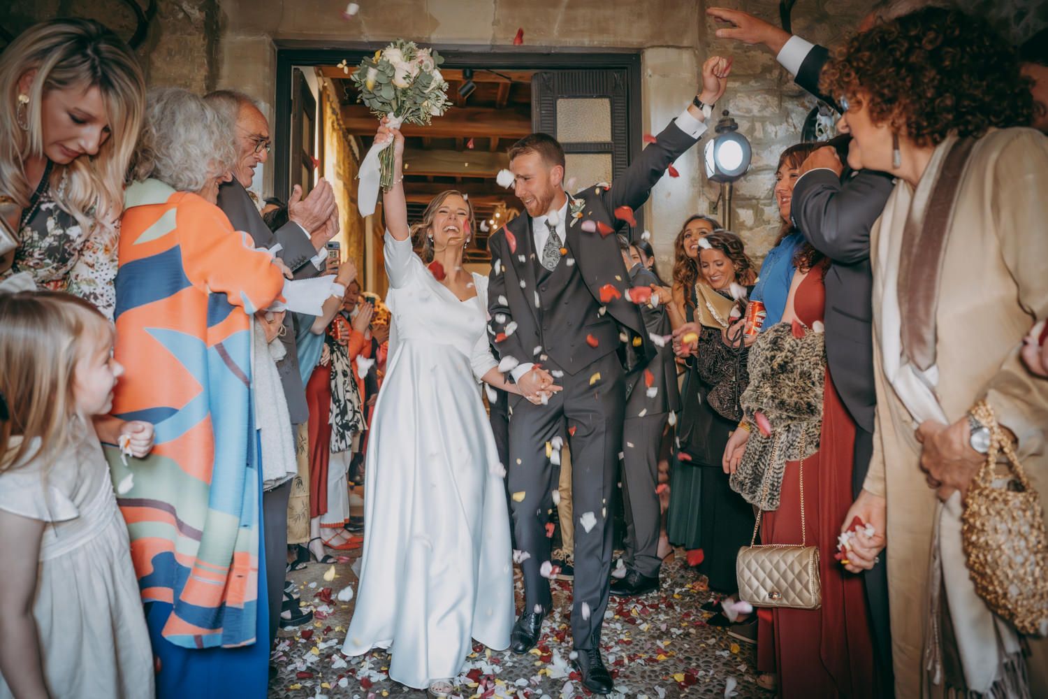 Los invitados a la boda arrojan confeti a una pareja mientras celebran durante una ceremonia en el interior.