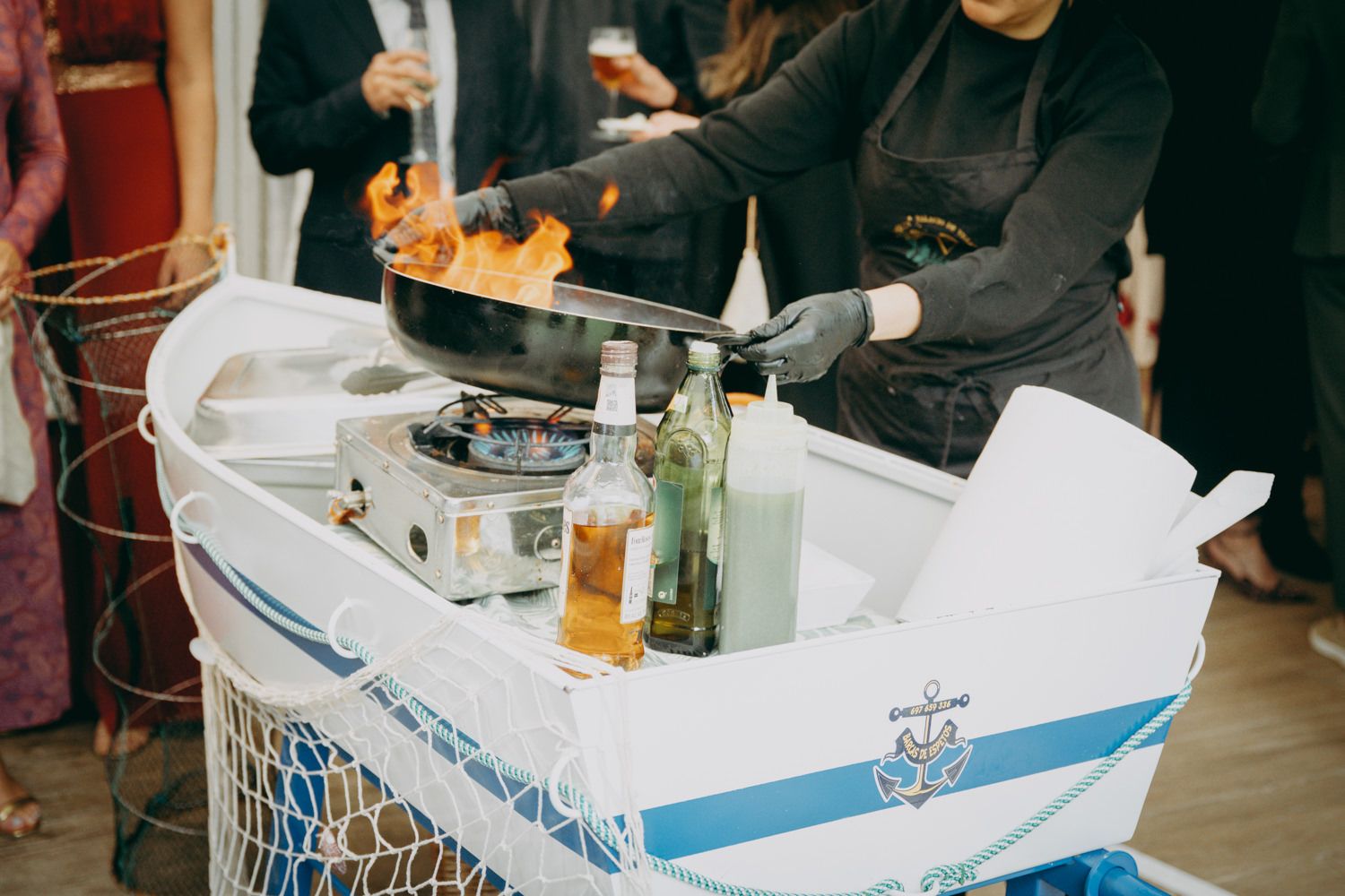 Una estación de catering con bebidas y suministros en un carrito blanco en un evento.