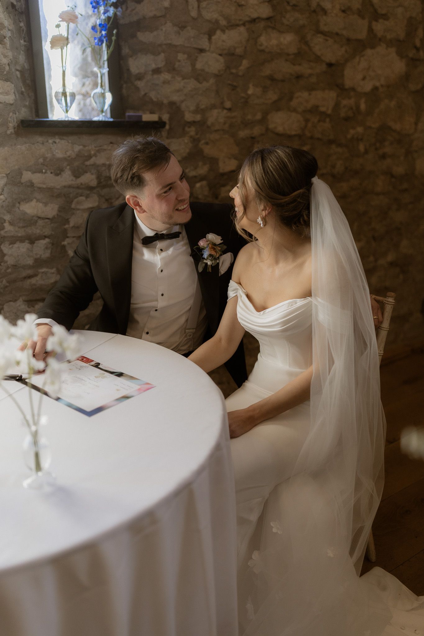 A couple shares an intimate moment at a rustic stone venue during their wedding reception.