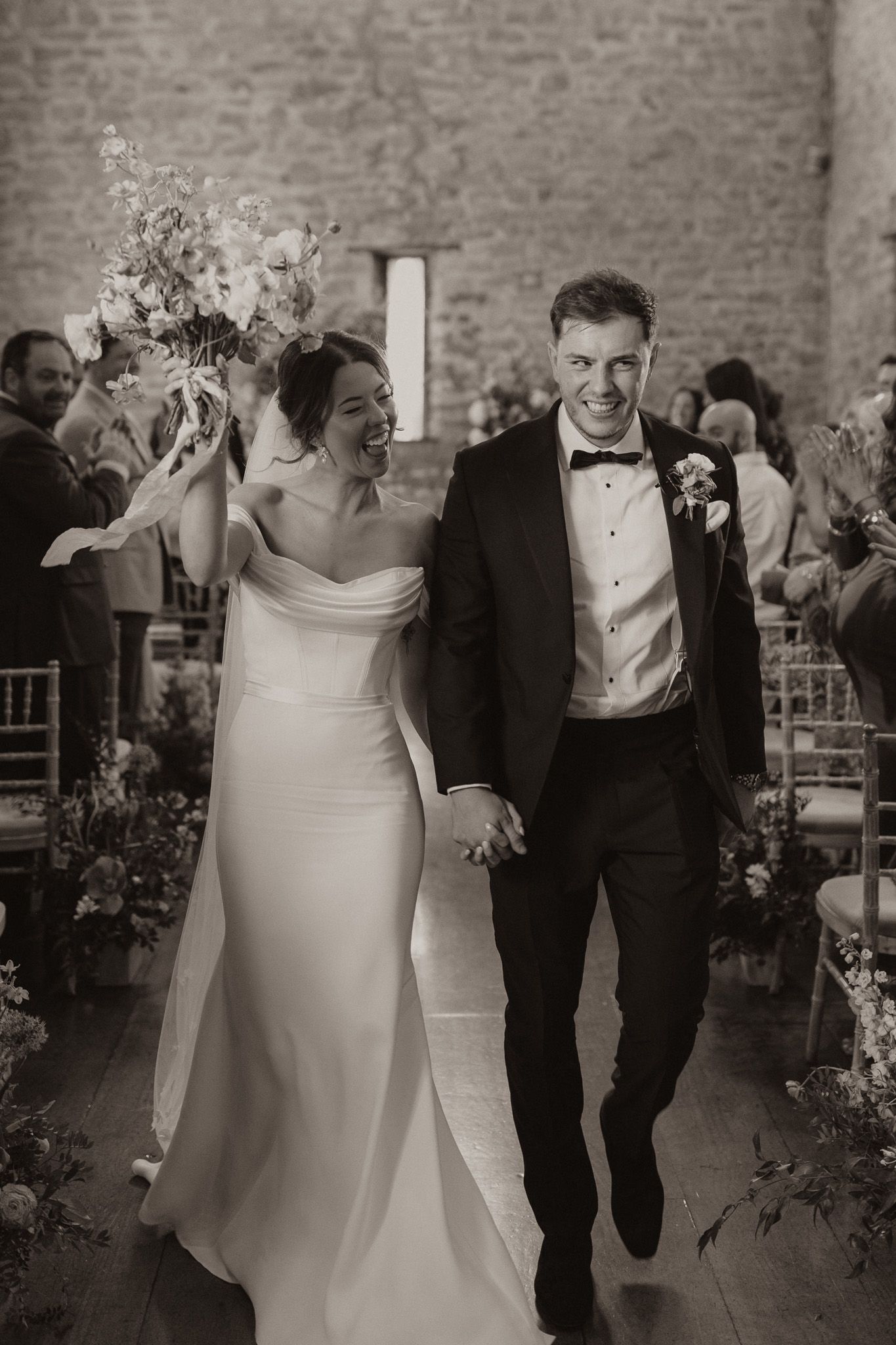 A joyful wedding celebration with newlyweds walking down the aisle in an elegant brick venue.