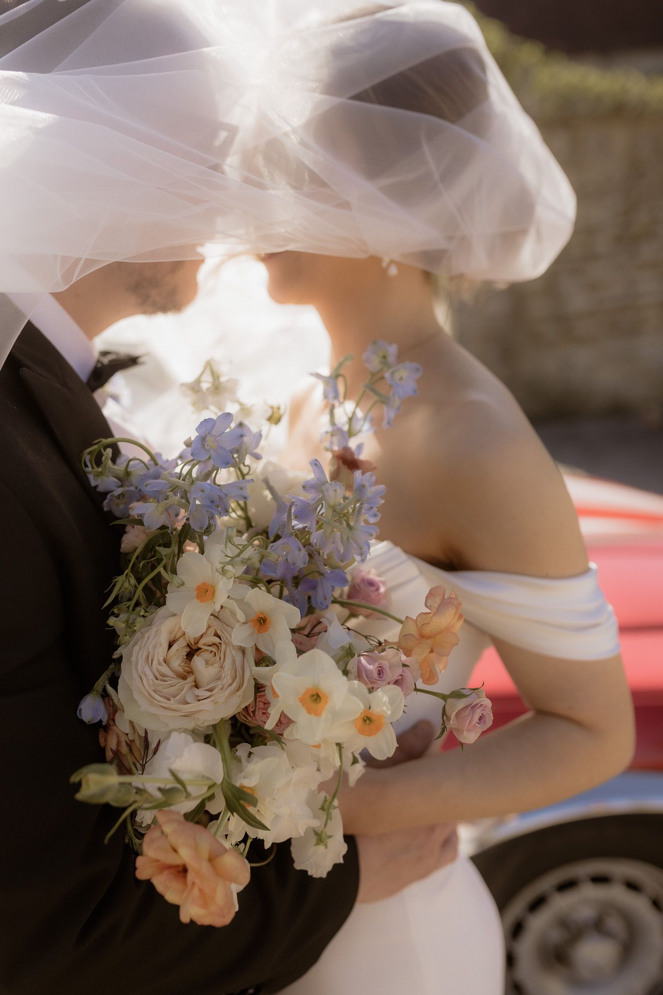 A close-up of a wedding bouquet with white roses and blue flowers against a bridal gown.