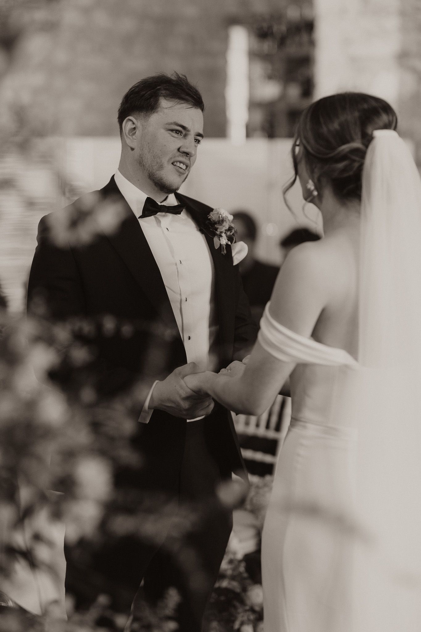 Black and white wedding photo capturing intimate moment between newlyweds during ceremony.