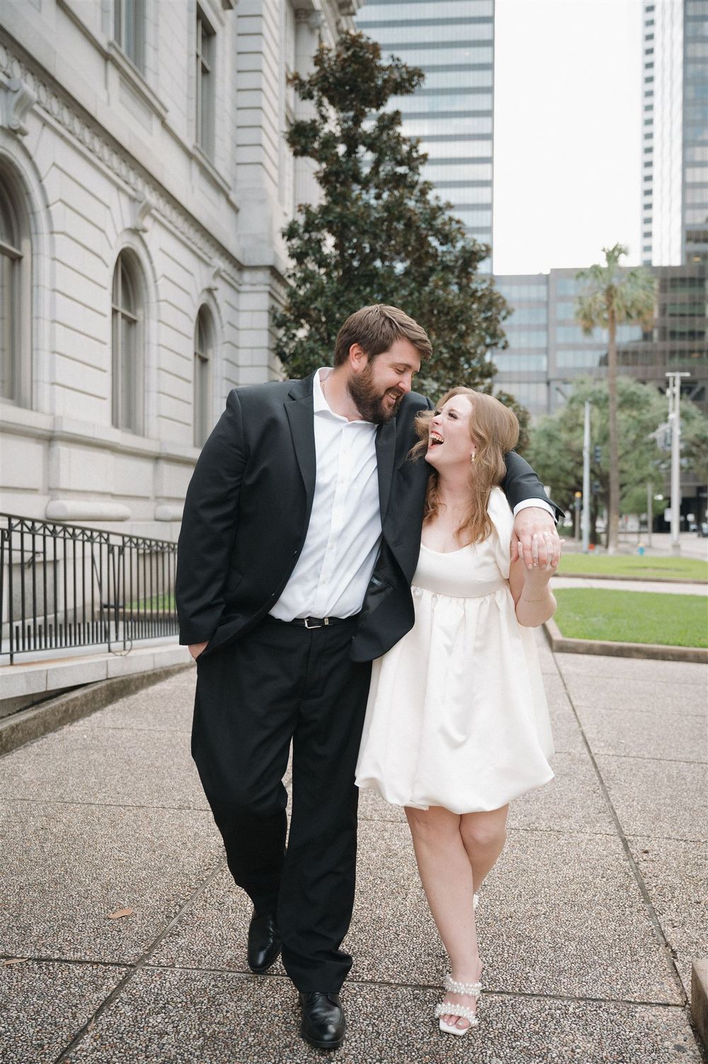 A happy couple sharing a candid moment outside a classic building in an urban setting.