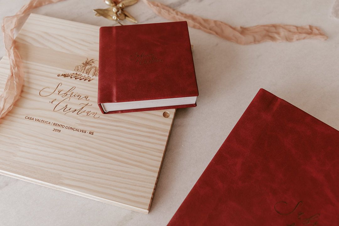 Red leather book and wooden board displayed on beige background in minimalist composition.