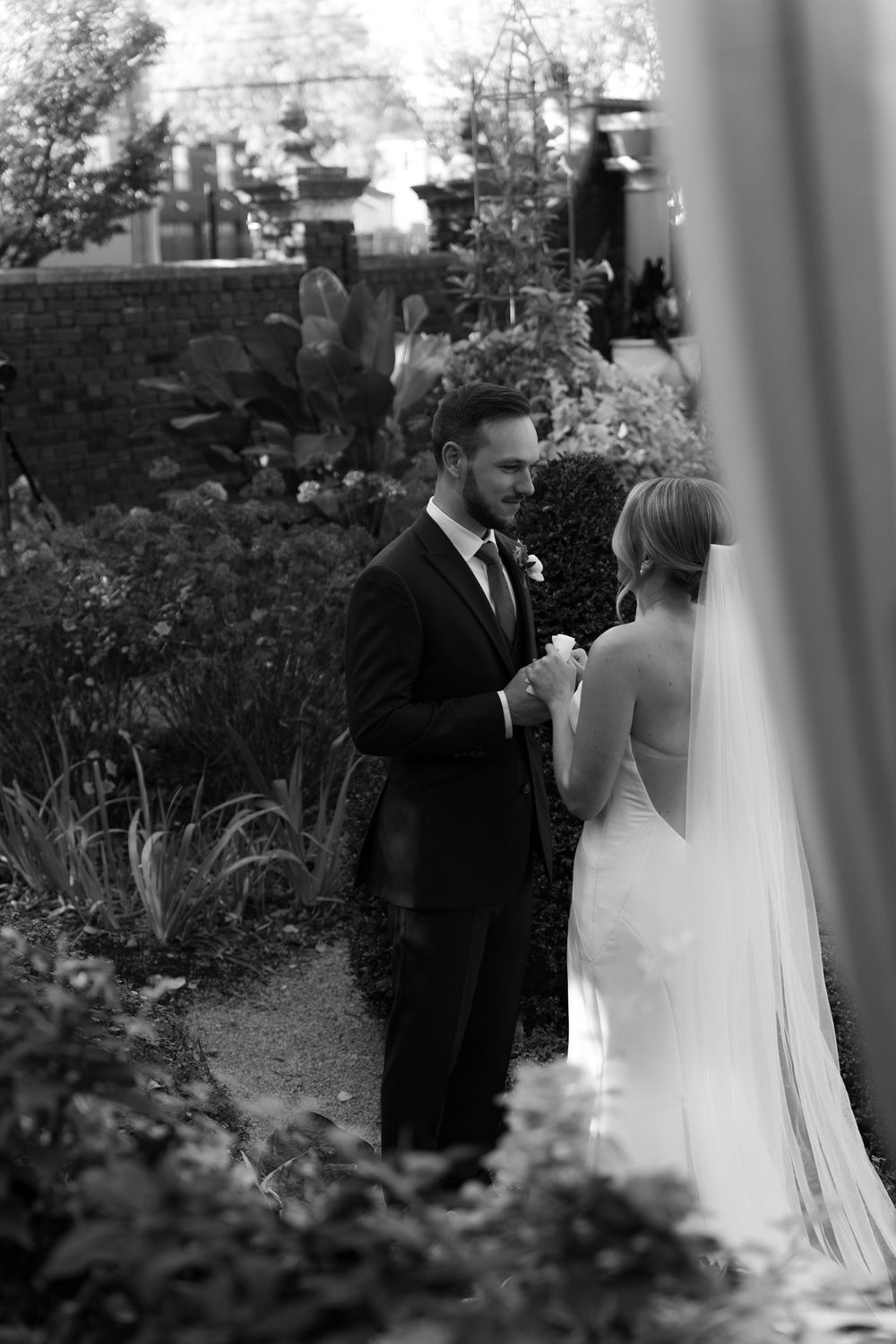 A bride and groom share an intimate moment in a garden setting during their black and white wedding ceremony.