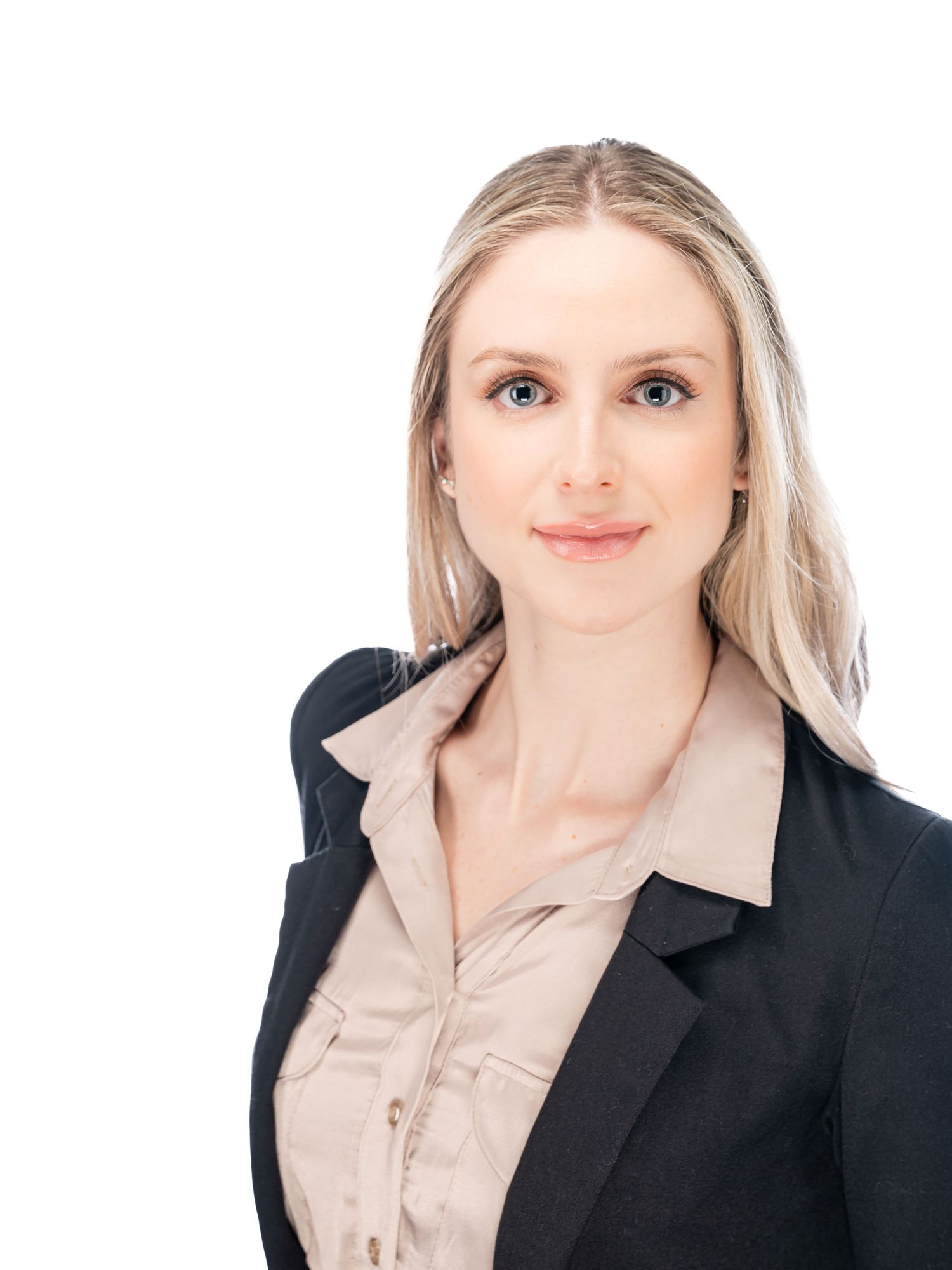 Professional portrait of a person in a black blazer and beige blouse smiling warmly against a white background.