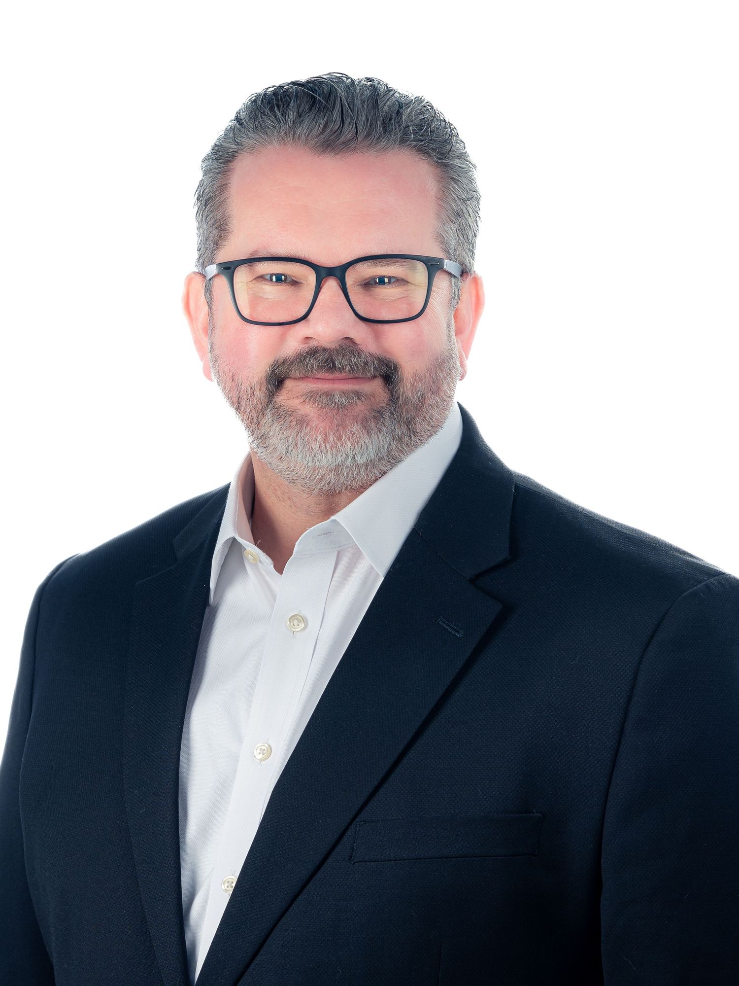 Professional headshot of person wearing black blazer, white shirt and glasses against light gray background.