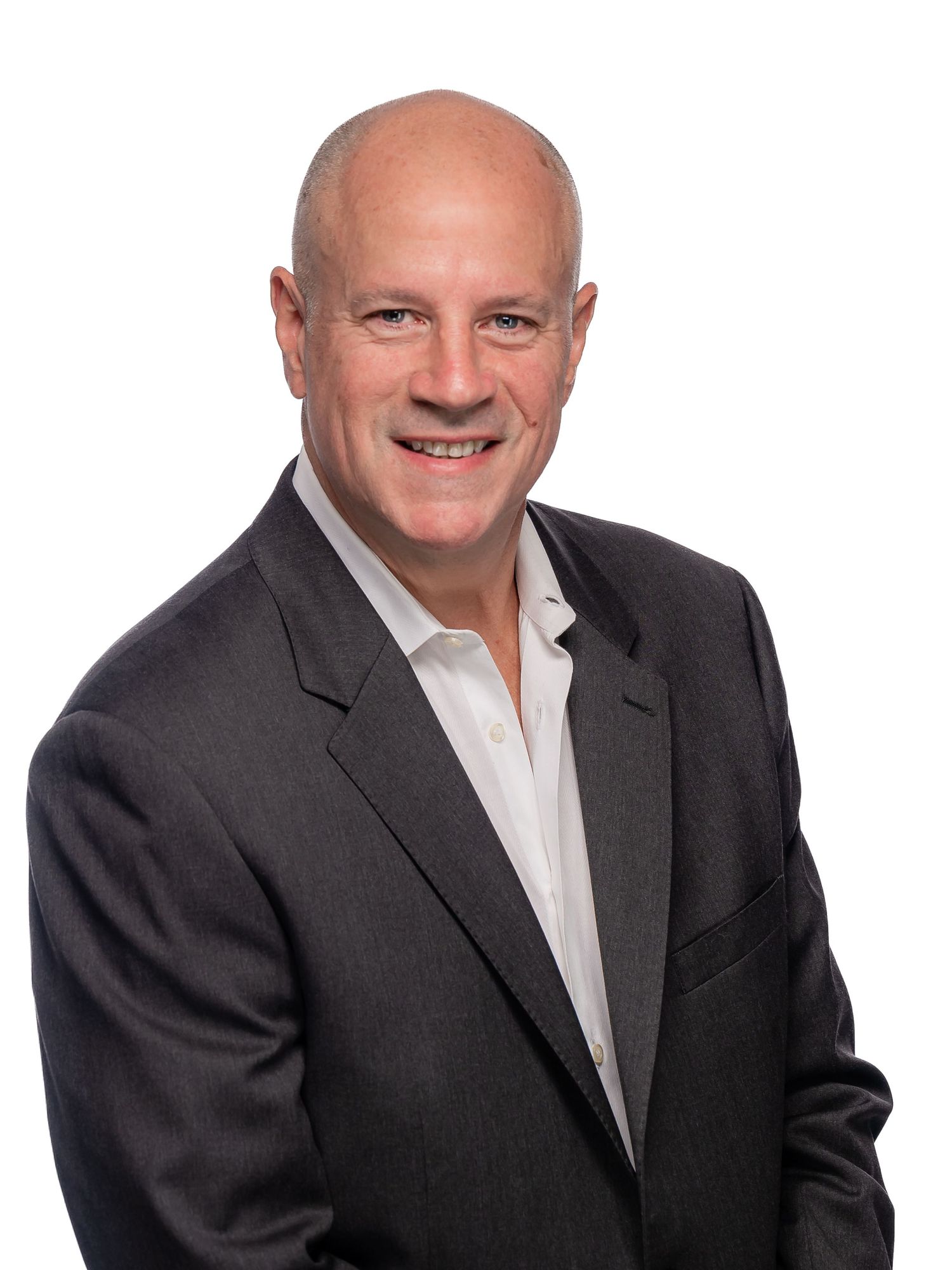 Professional headshot of person in dark suit jacket and light colored shirt smiling warmly against neutral background.