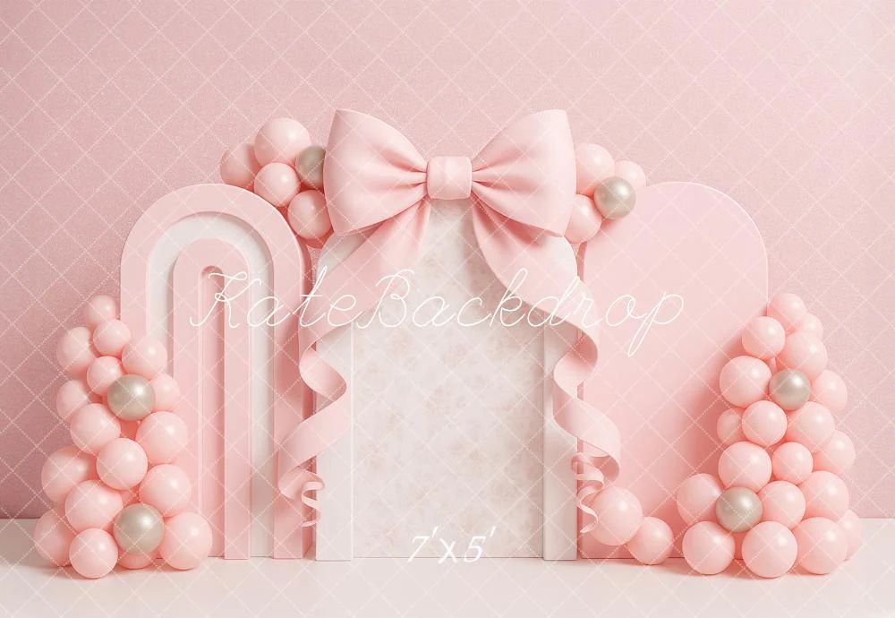 Pink birthday party backdrop with balloons, arches and bow decoration in monochromatic pastel design.