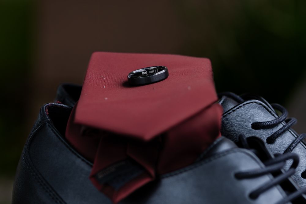 mans wedding ring with I love you written on it resting on tie