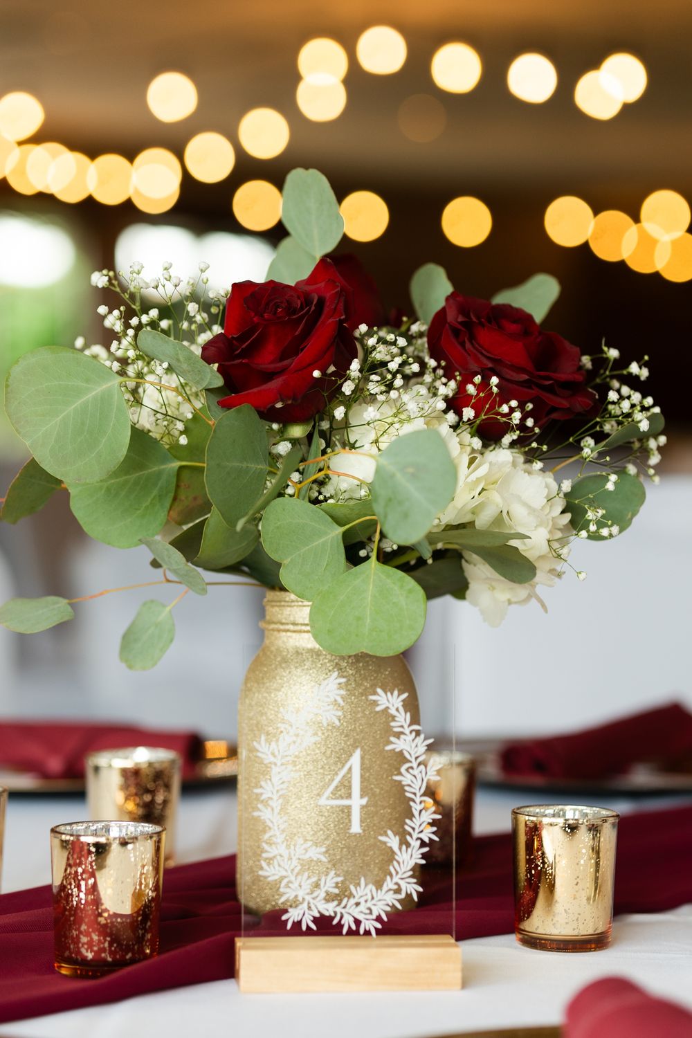 wedding table decor, roses in gold vase with gold candle holders and a number 4 table number