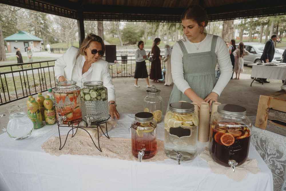 Drink station with glass dispensers filled with colorful beverages at an outdoor reception.