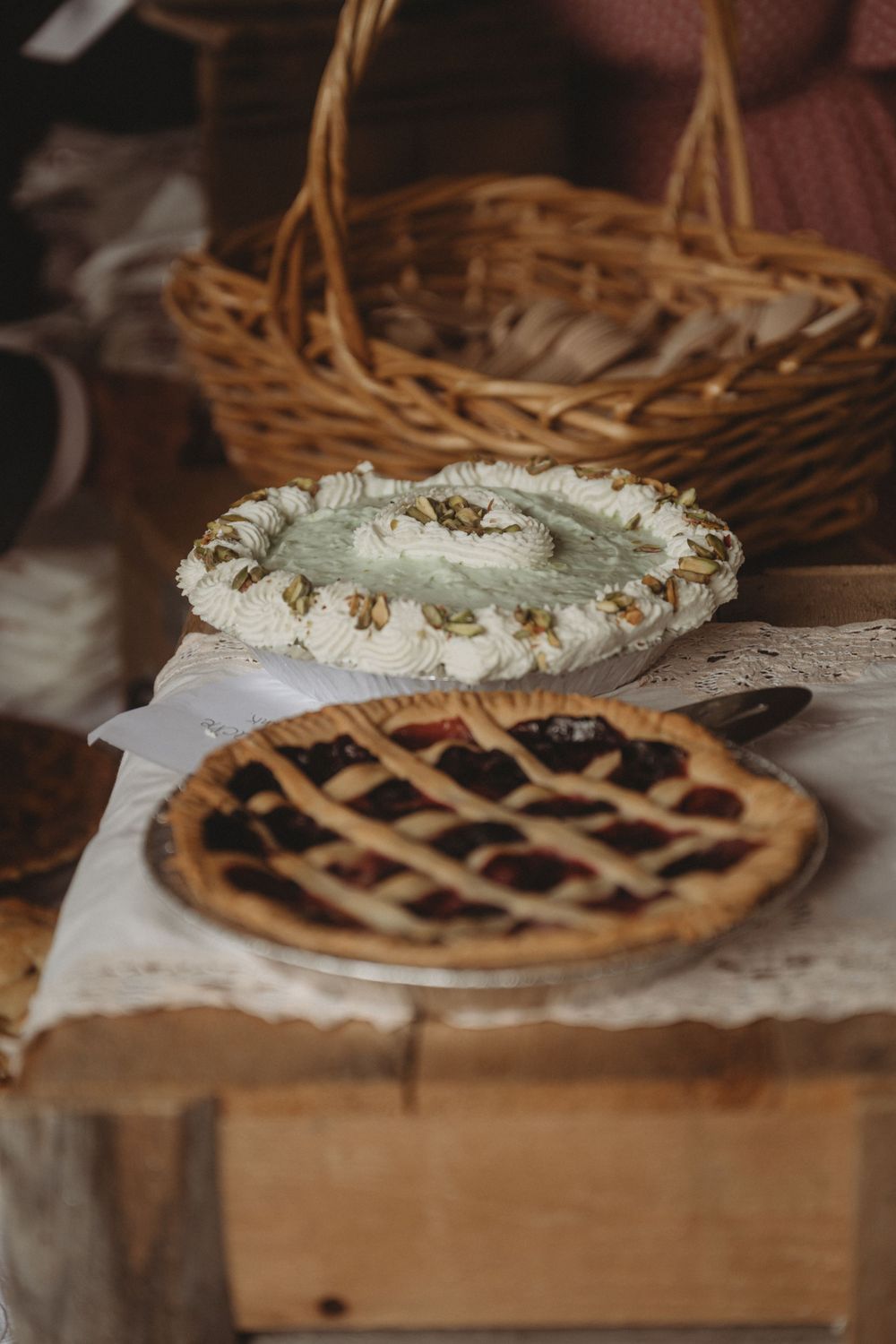 Two homemade pies displayed on rustic wooden surface with wicker basket in background.