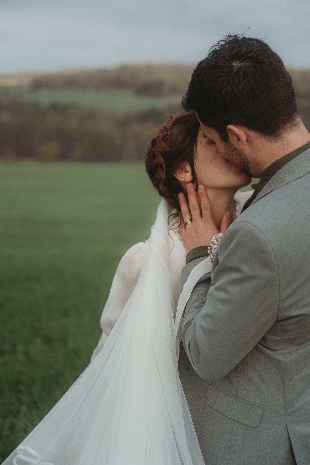 An intimate wedding portrait showing a couple embracing in a grassy field.