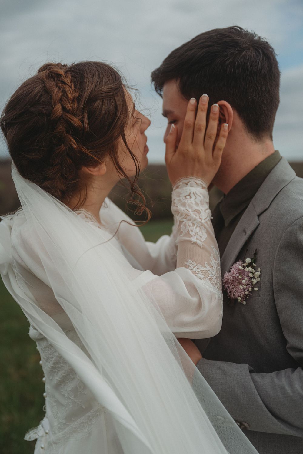 An intimate wedding portrait showing intricate braided hair and lace sleeve details.