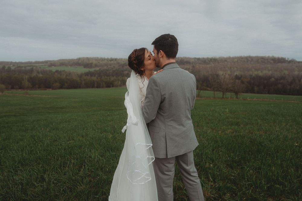 A loving embrace between newlyweds in a serene countryside setting.
