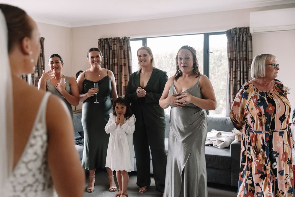 Wedding guests share an emotional moment together in a sunlit room.