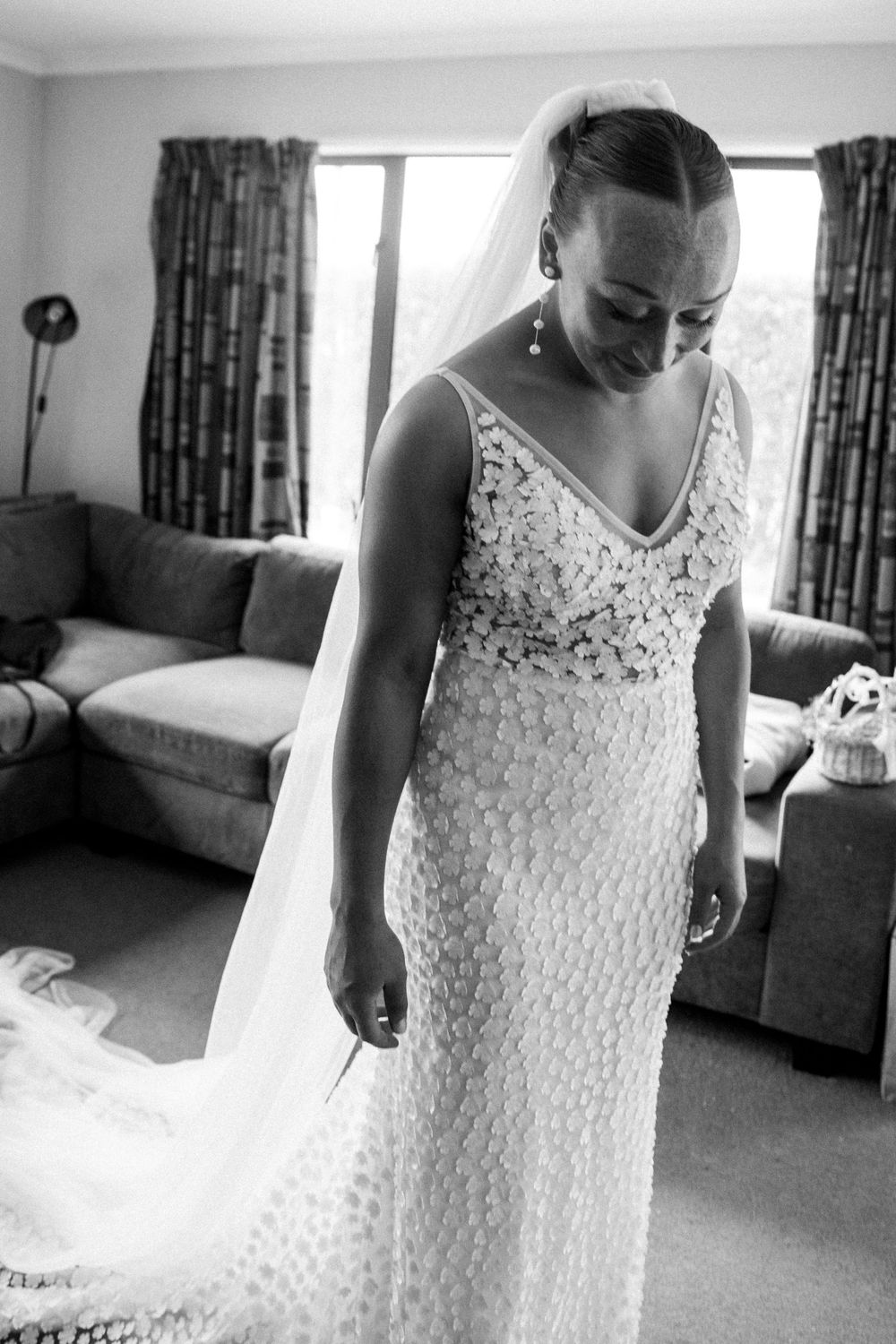 A black and white portrait showcasing an elegant beaded wedding gown with a flowing train.