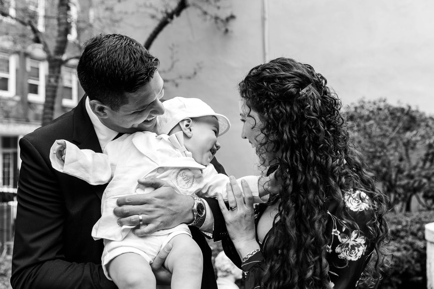 Black and white photo capturing intimate family moments after a baptism.