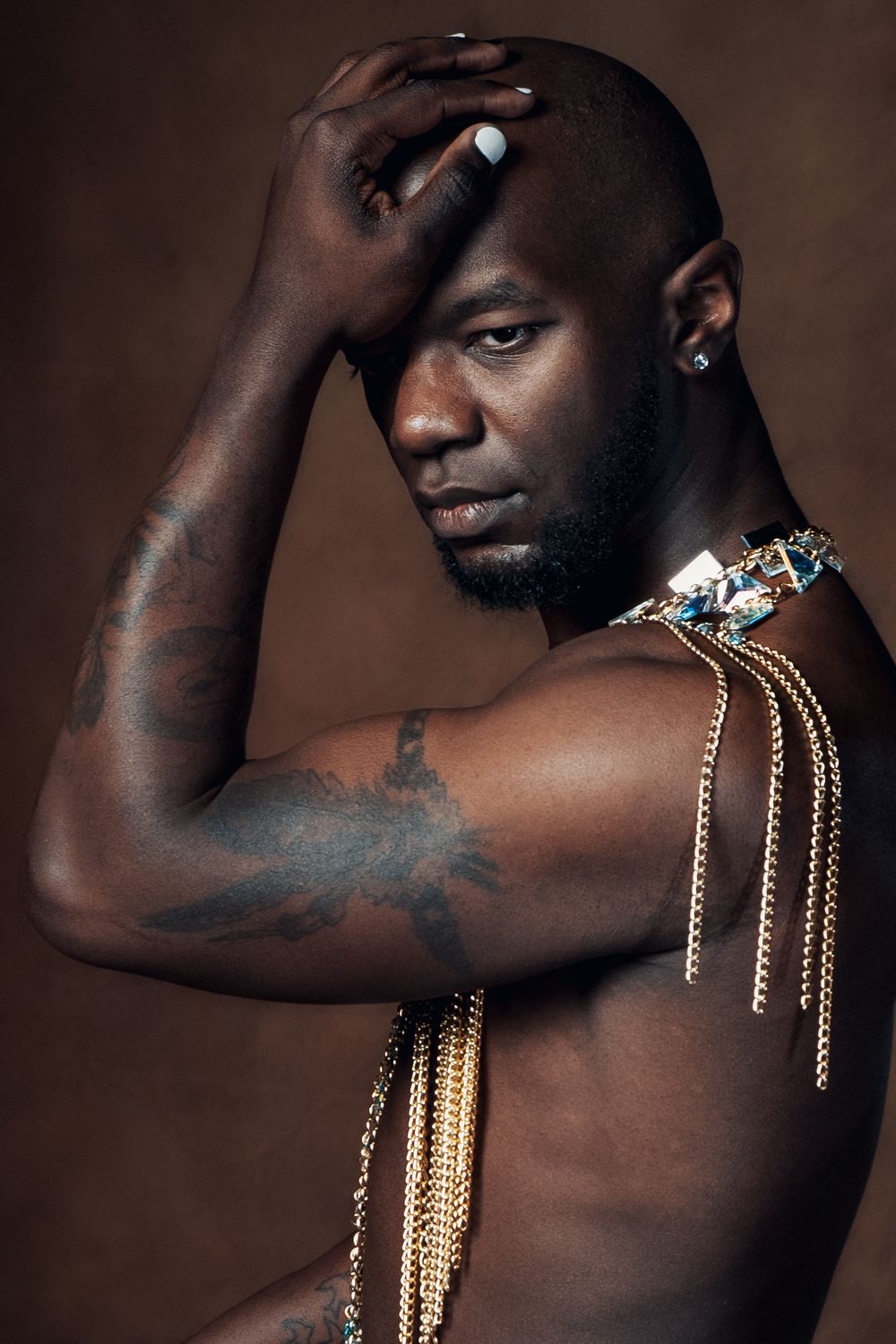 Artistic portrait highlighting gold jewelry chains against dark skin in studio lighting.