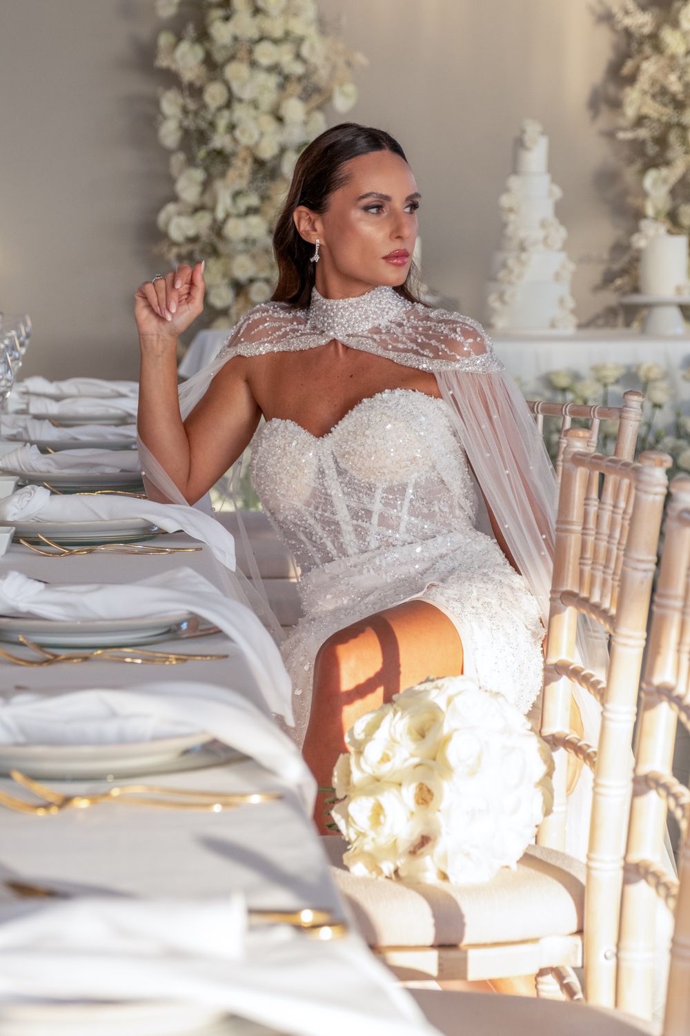 Elegant table setting with white floral arrangements and chiavari chairs in soft lighting.