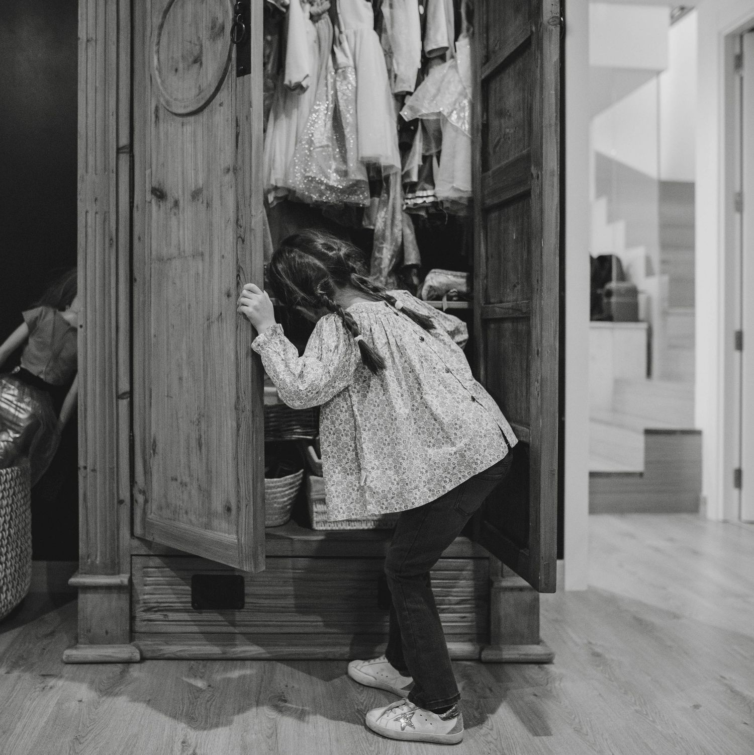 niña con trenzas buscando y elegiendo disfraz en armario. fotografía cotidiana infantil