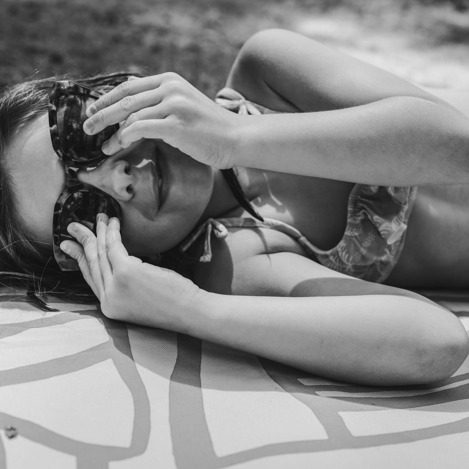 fotos en pareja blanco y negro en madrid. picnic verano. boca del asno. niña tumbada el alfombra jugando con gafas de su madre.