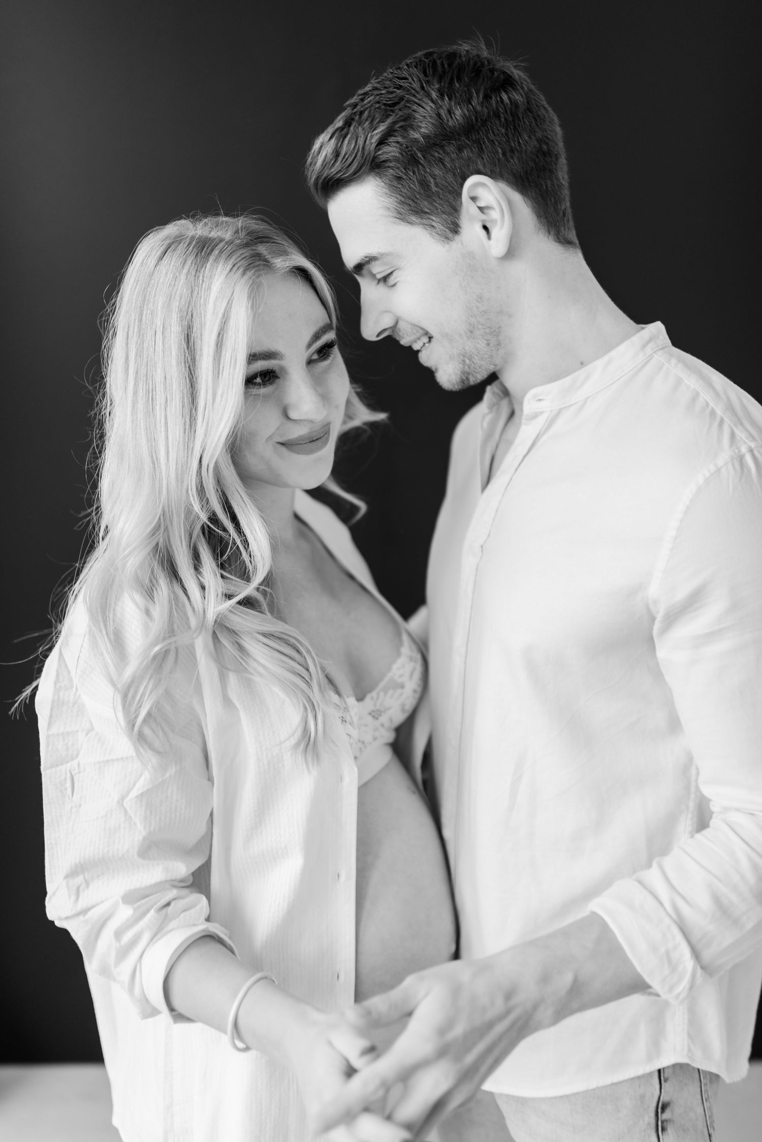Black and white portrait series showing couple in white clothing embracing intimately in romantic poses.