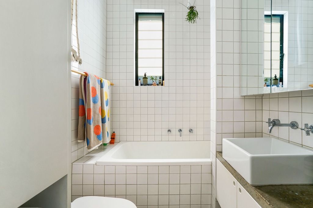 Modern bathroom interior with white tile, floating sink, and polka dot shower curtain.