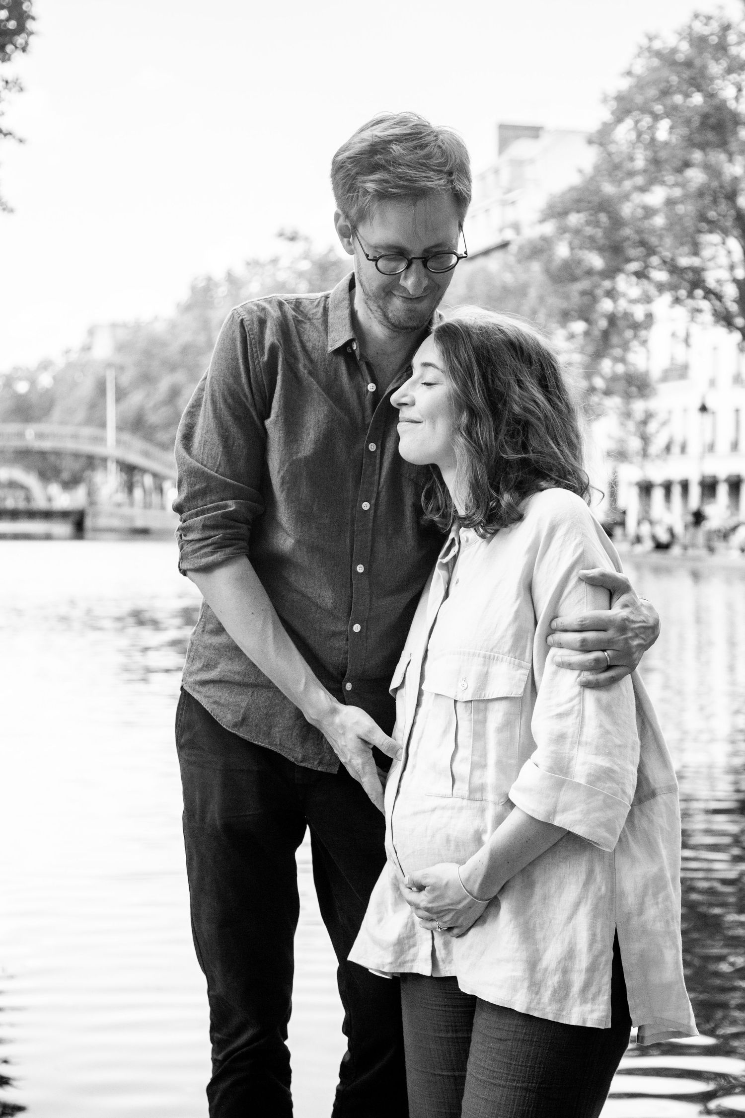 Intimate black and white portrait of couple embracing by waterfront.