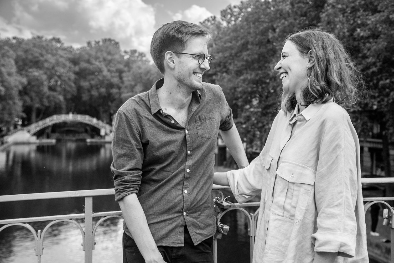 Candid moment of couple laughing together on bridge over canal.