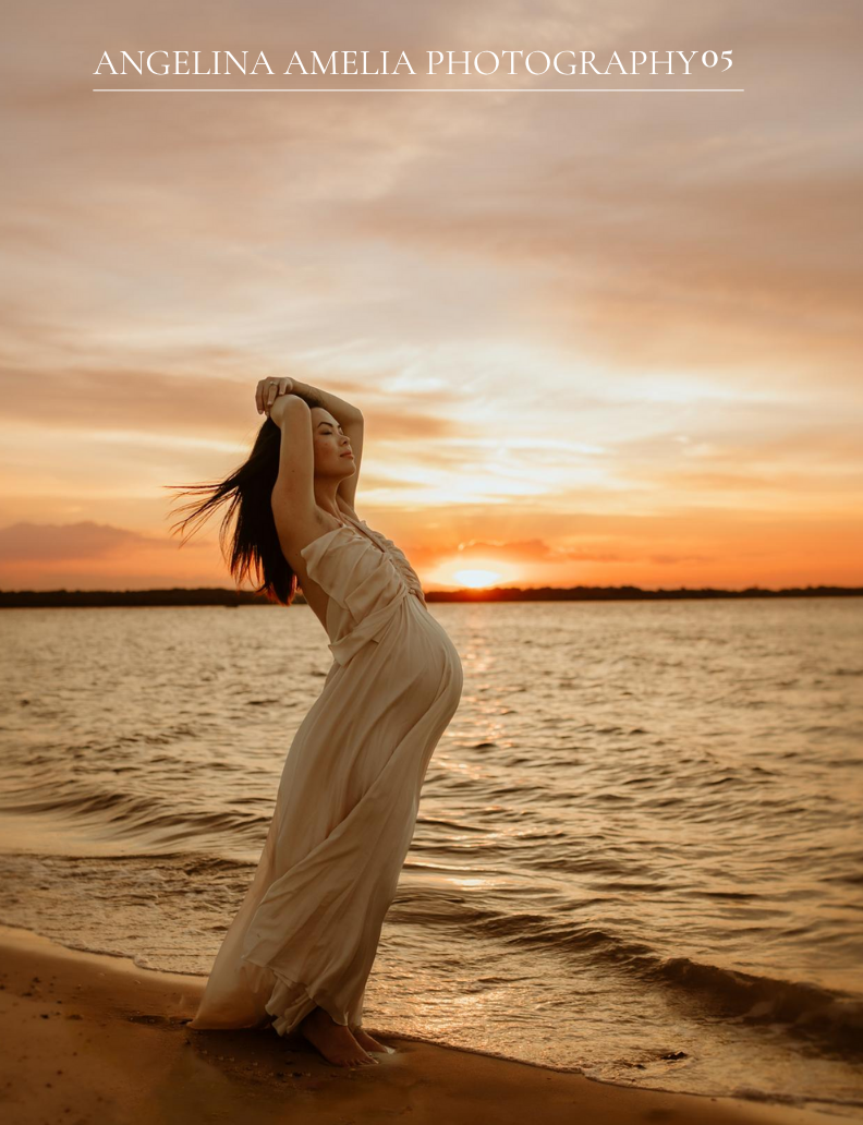 Silhouetted figure in flowing dress poses dramatically on beach at sunset with orange sky reflecting on rippling water.