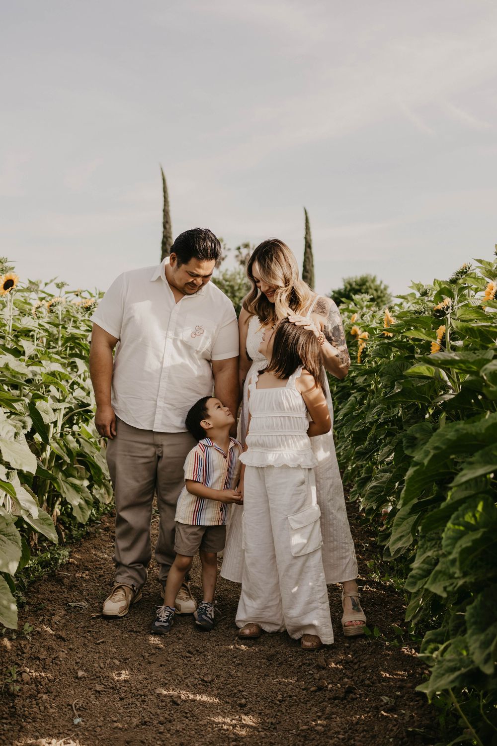 Family standing together in a sunflower field during a rustic outdoor photo session.