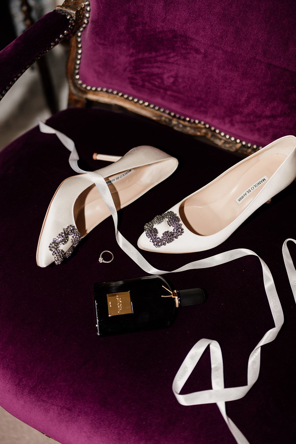 Luxury bridal shoes with crystal embellishments displayed against a deep purple velvet background.
