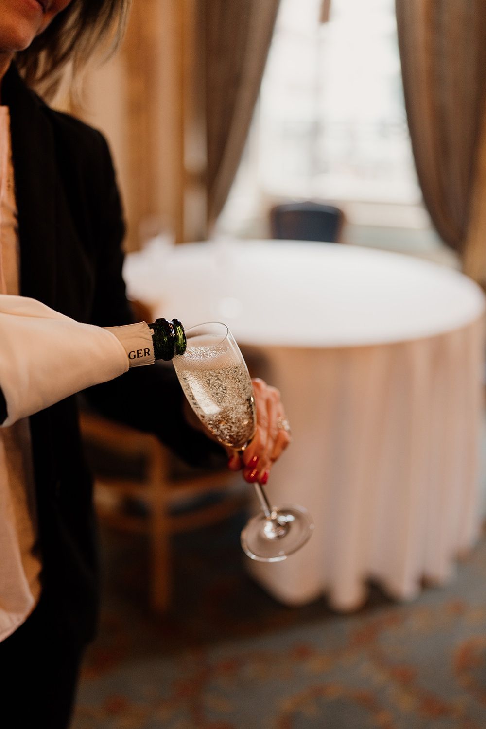 Someone pouring sparkling champagne into a delicate glass flute at an elegant event.