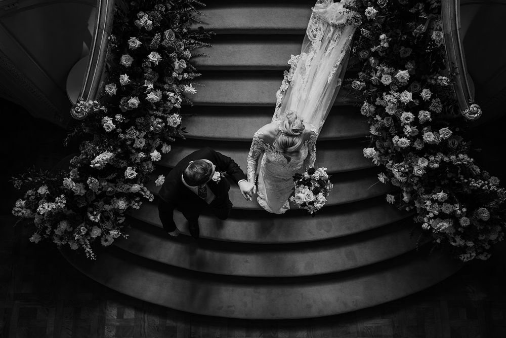 An ornate wedding aisle with floral arrangements lining the steps and a long white dress train flowing down.