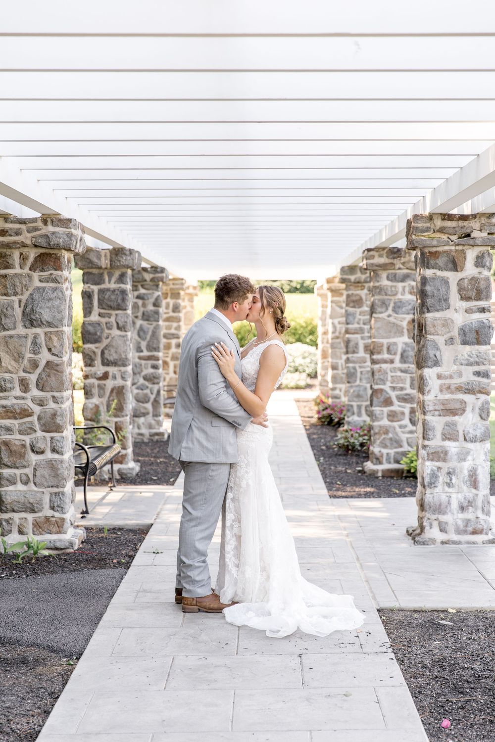 A romantic wedding couple shares a tender moment in front of an elegant stone archway during a photo session.
