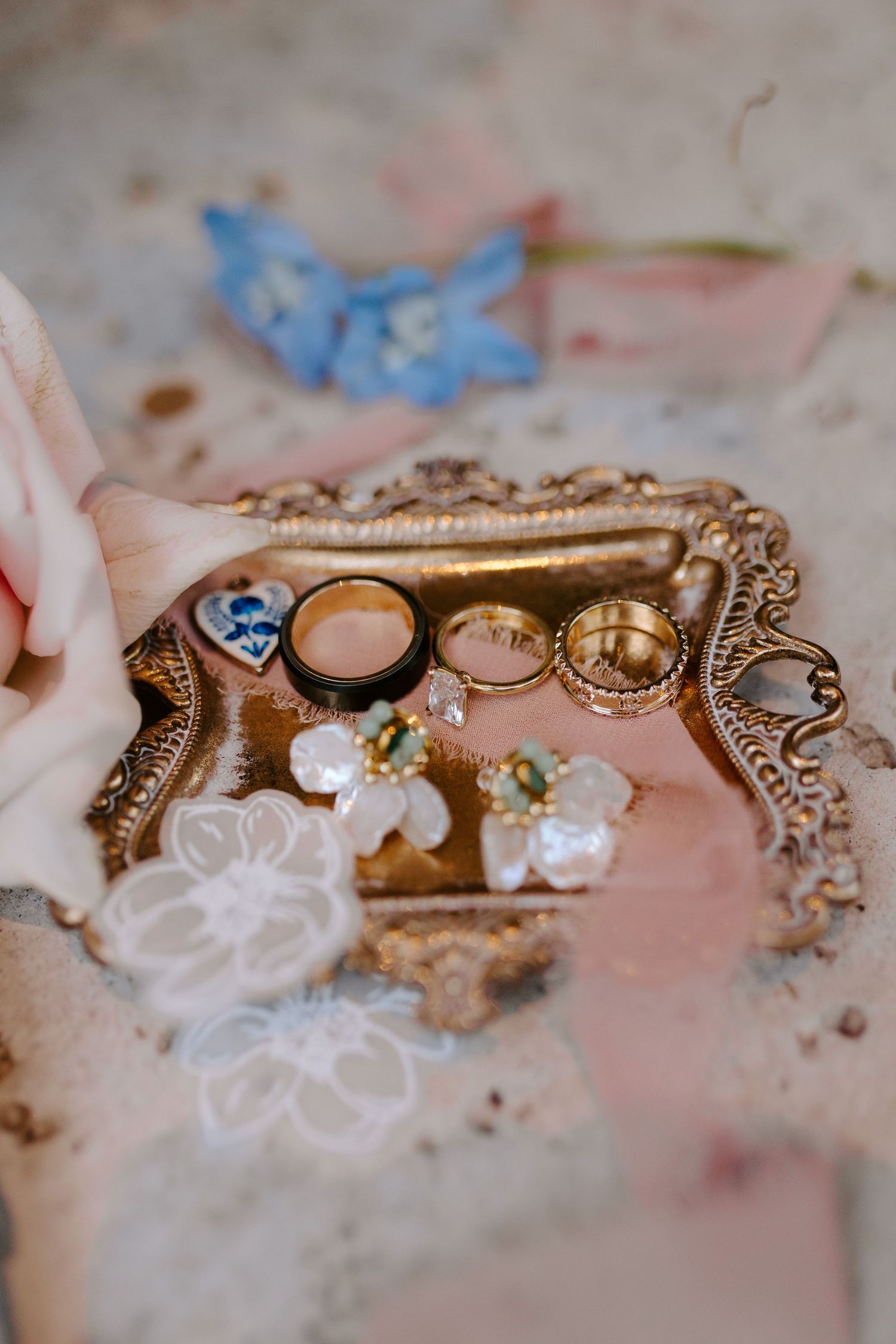 Wedding rings and jewelry displayed on an ornate vintage golden tray with delicate floral details.