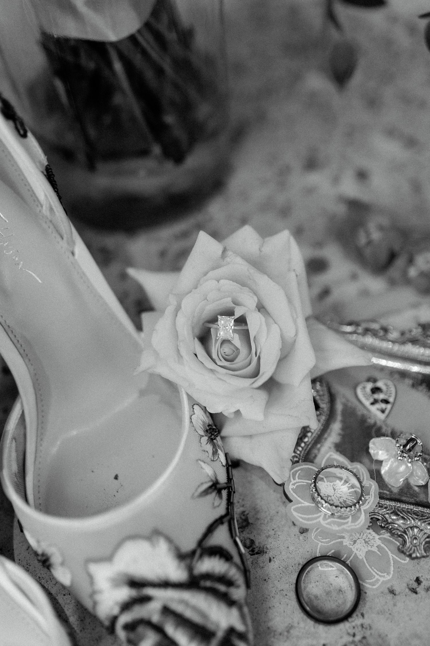 Black and white detail shots of wedding rings nestled among white roses.