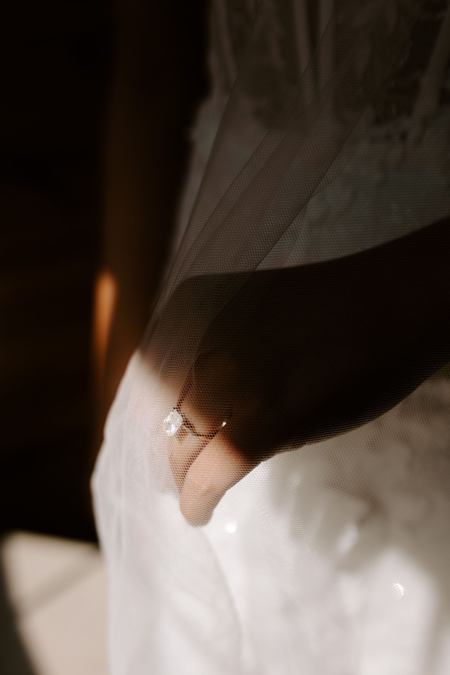 Close-up detail shot of a delicate pearl bracelet against white fabric in moody lighting.
