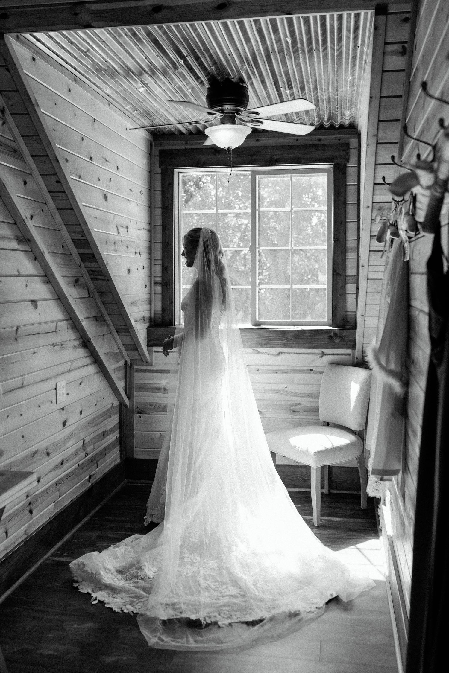 Black and white photos of a wedding dress displayed in a wooden cabin with natural window light.